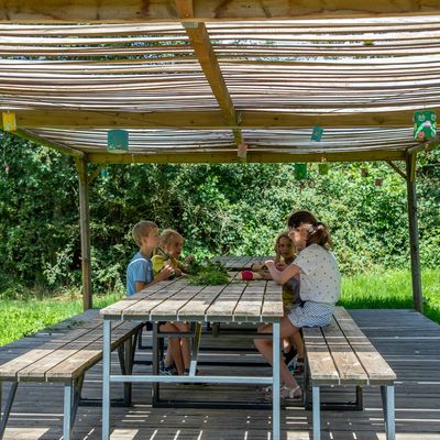 Des enfants travaillent sous la pergola en bois, dans le jardin