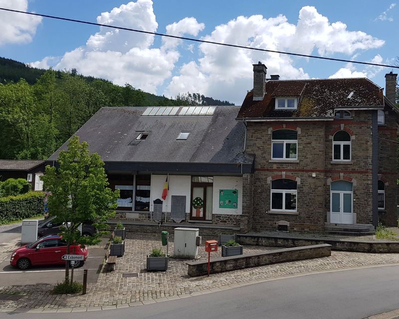 L'école de Moulin du Ruy, bâtiment en pierre au pied des collines boisées
